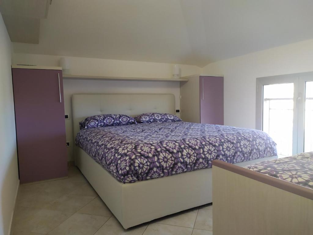 um quarto com uma cama com um edredão roxo em La mansarda della luna em Pietra Ligure