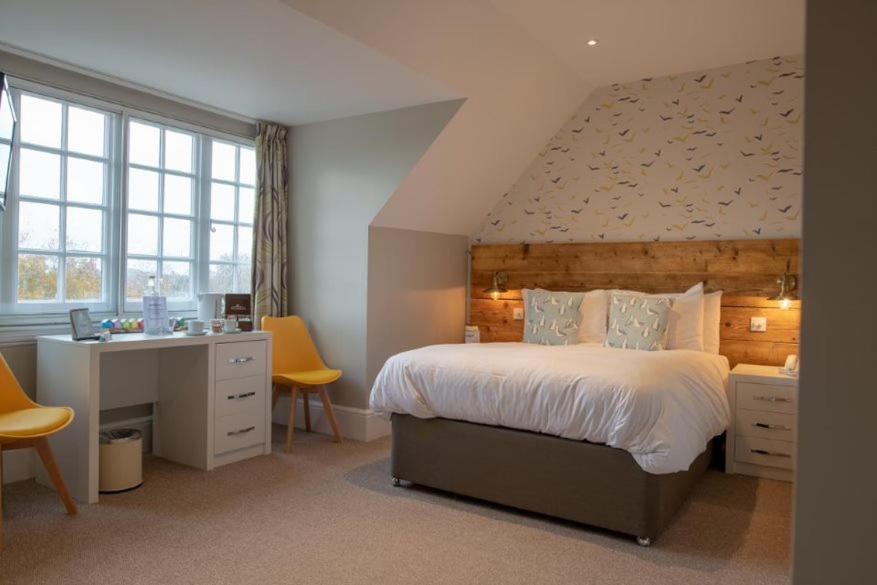 a bedroom with a large bed and a desk andwindows at The Randolph Hotel in Southwold