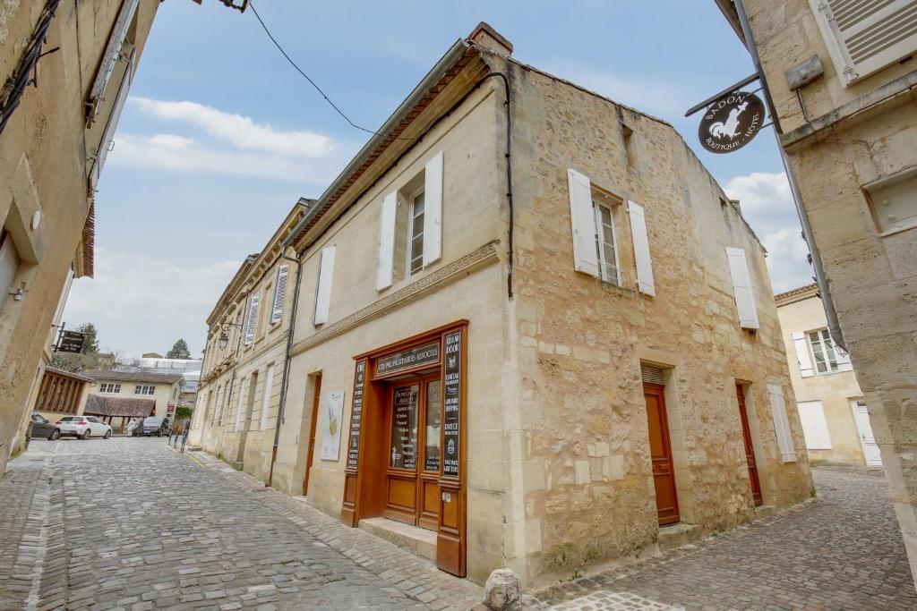 um antigo edifício de pedra numa rua de calçada em Logis Andraud Studios em Saint-Émilion