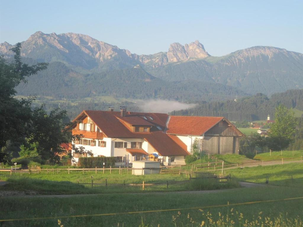 a house in a field with mountains in the background at Haus Echtler in Hopferau