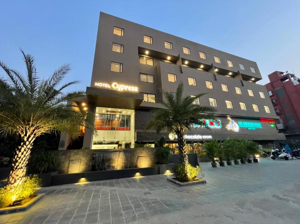 un hotel con palmeras frente a un edificio en HOTEL CYPRESS en Nadiād