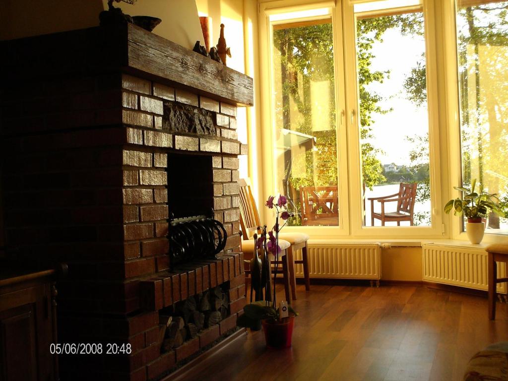 a living room with a brick fireplace and windows at Ezerkiemis in Trakai