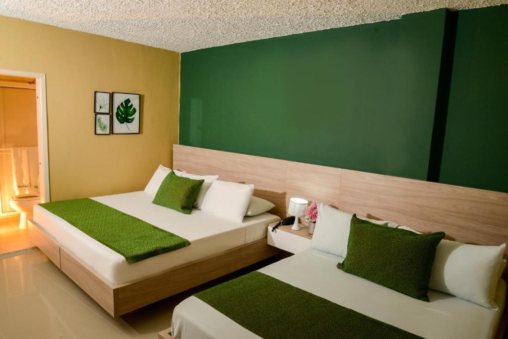 two beds in a room with green and white at Hotel Prado 34 West in Bucaramanga