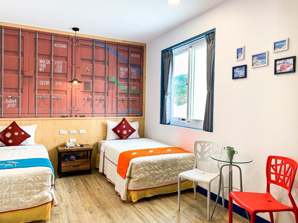 a bedroom with two beds and a table and a window at Ocean Star B&amp;B in Kenting