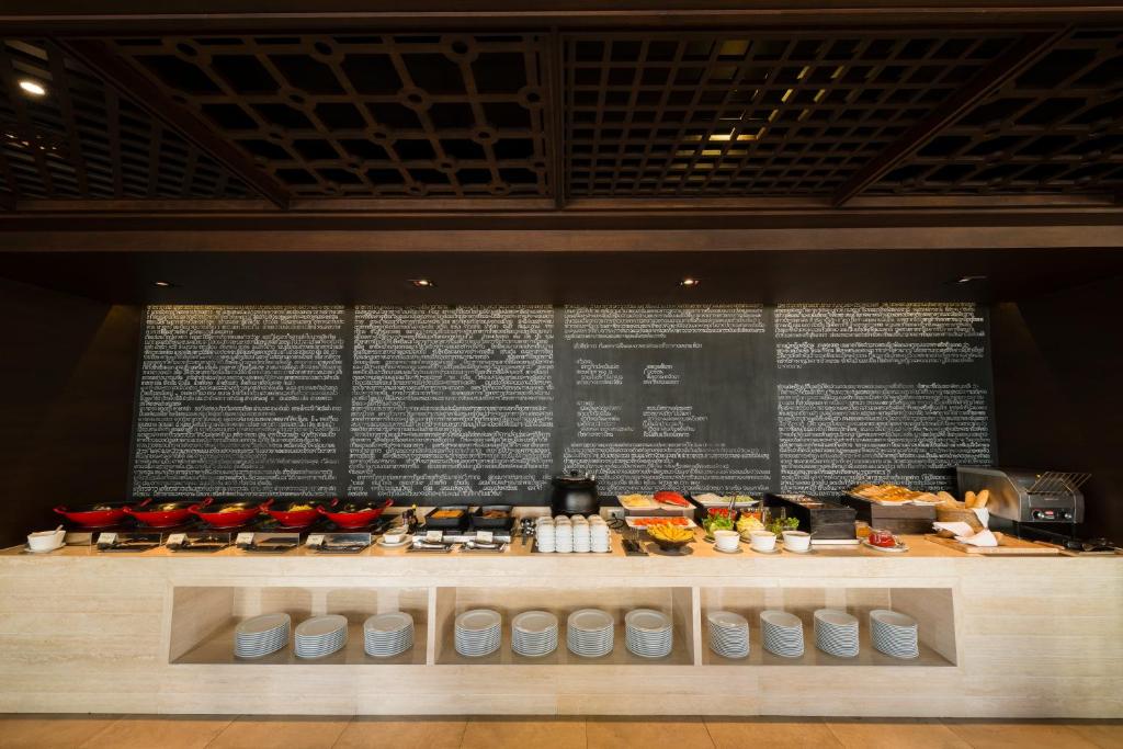 A hotel buffet counter set beneath a large wall menu.