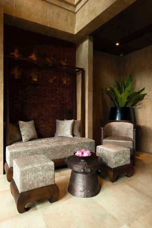 A hotel seating nook with a built-in sofa, armchair, ottomans, and a decorative table.