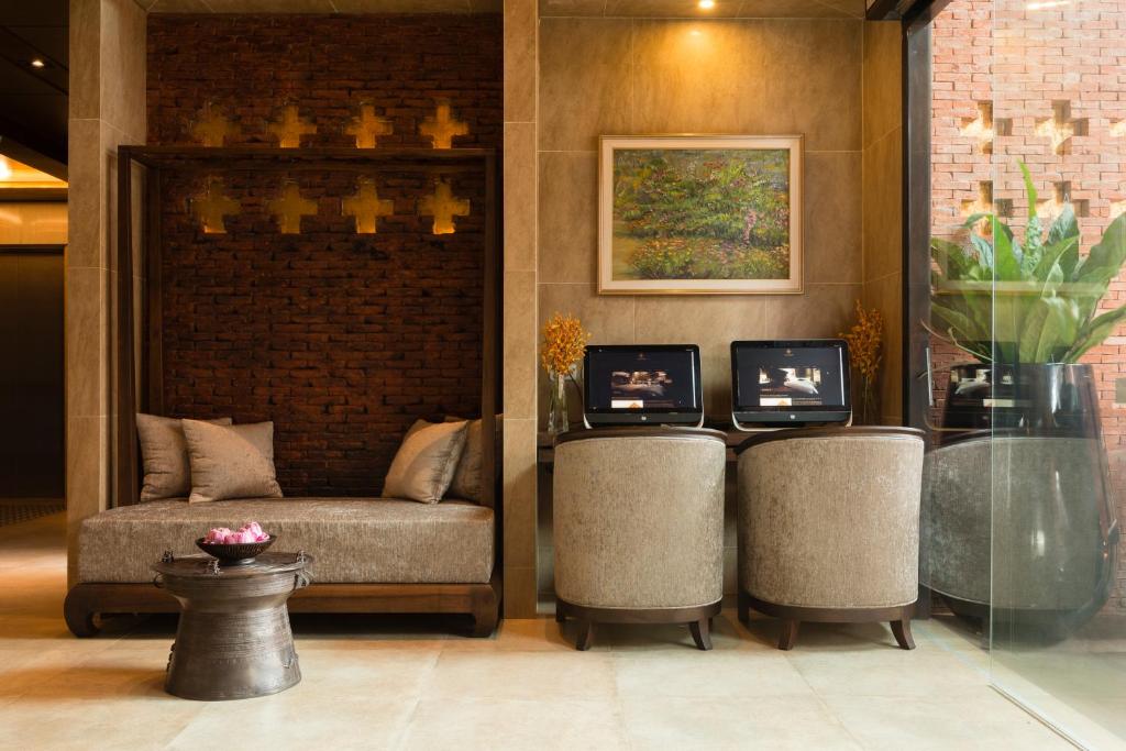 A compact lobby seating area with a sofa, two chairs, and computer stations.