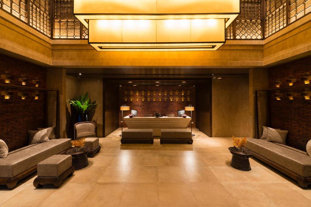 A spacious lobby lounge with sofas, low tables, and a reception desk beyond.