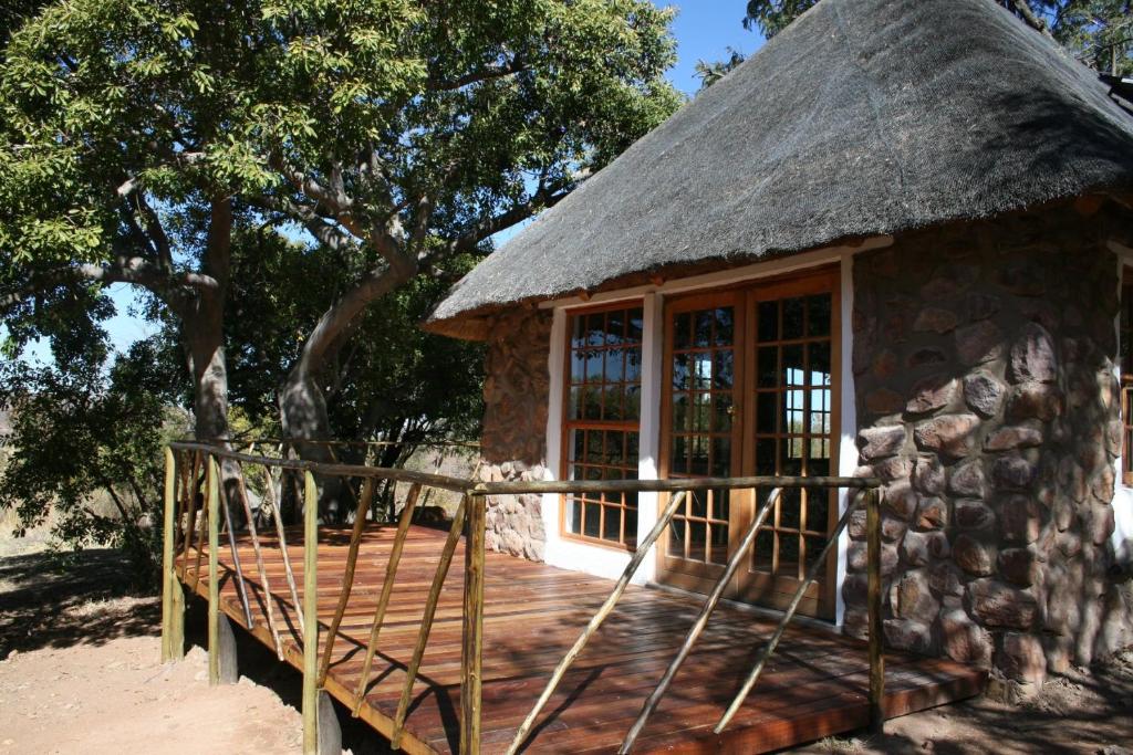 eine Hütte mit einem Strohdach und einer Holzterrasse in der Unterkunft Griffons Bush Camp in Thabazimbi