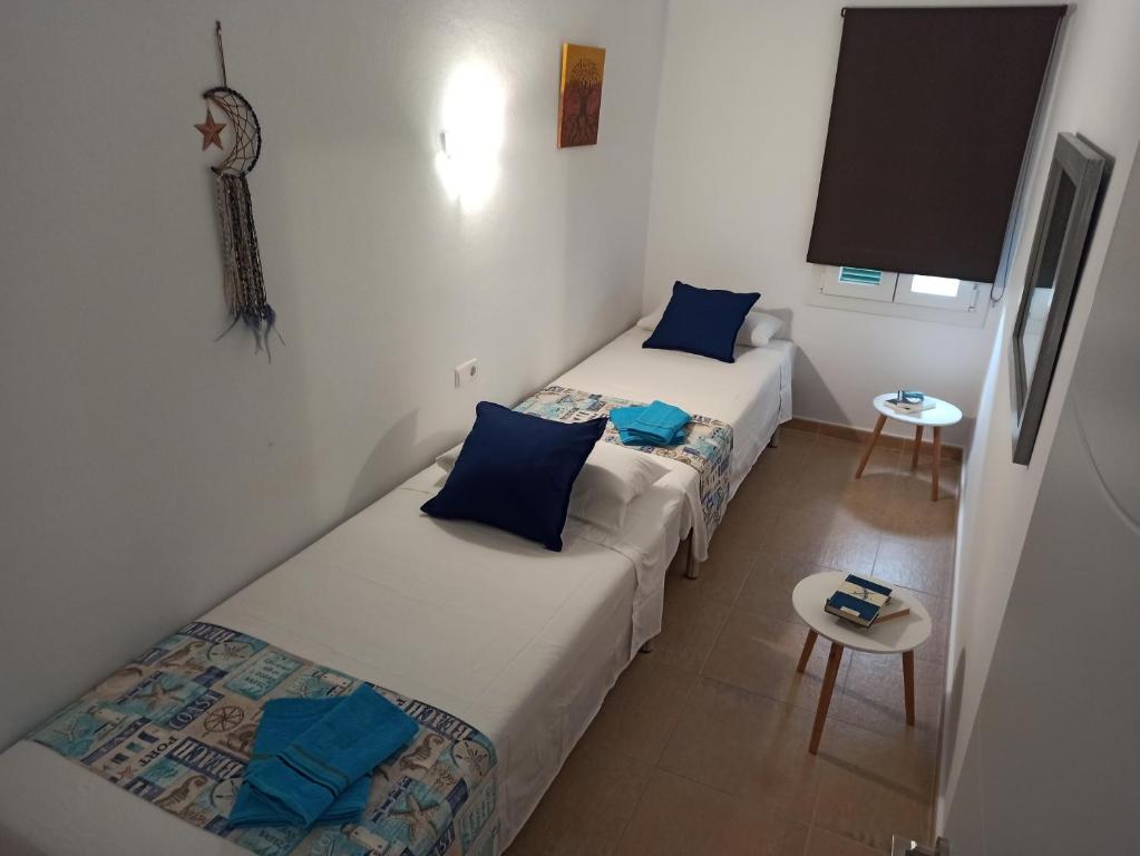 Habitación pequeña con 2 camas individuales y mesa. en Garbí & Xaloc apartamentos en Cala Galdana