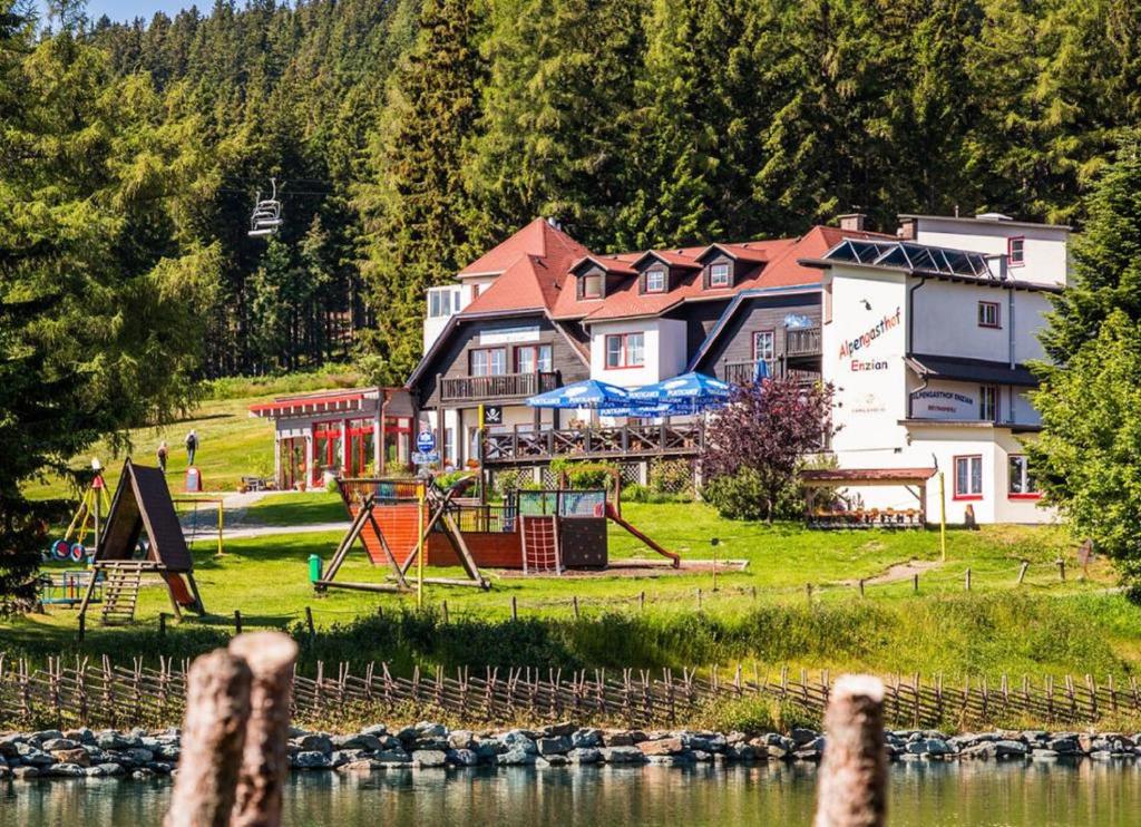 a large building with a playground next to the water at Alpengasthof Enzian GmbH in Mönichkirchen