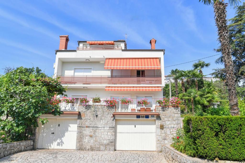 a white house with a gate and a garage at Apartment Amelie in Opatija