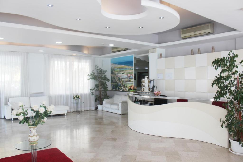 a living room with white furniture and plants in it at Hotel Marittima in Rimini