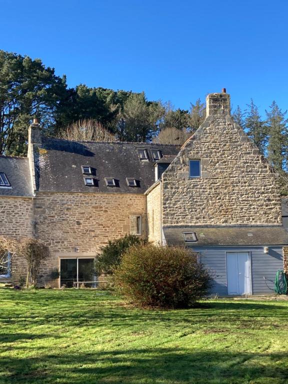 un antiguo edificio de piedra con un garaje en un campo en Maison près de l'Océan, en Pont-Croix