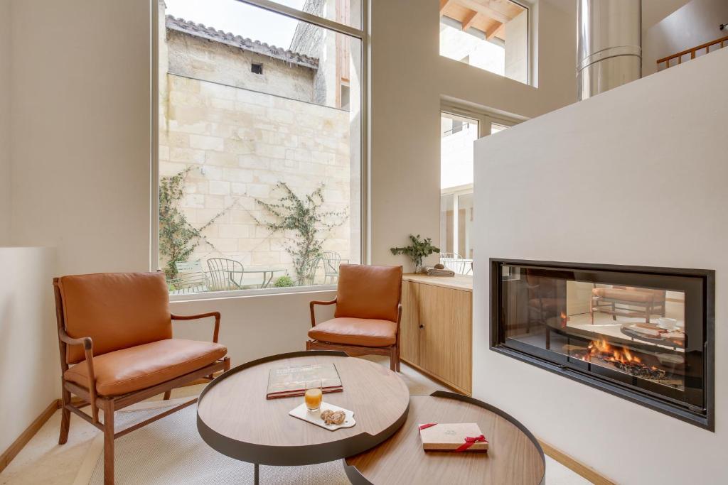 a living room with a fireplace and two chairs at Badon Boutique Hotel in Saint-Émilion