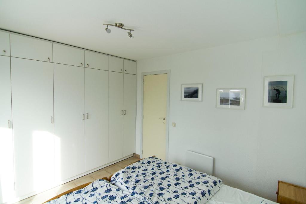 デ・ハーンにあるAppartement zeepolder IIIの白いキャビネットとベッド付きのベッドルーム1室