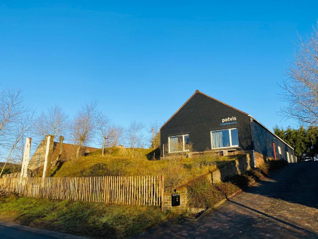 a house on top of a hill with a fence at Potvis in Oostduinkerke