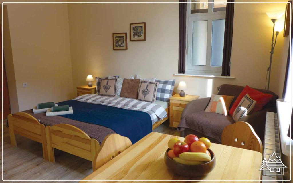 Un dormitorio con una cama y una mesa con un bol de fruta en Przystanek Rabka - Apartamenty w centrum en Rabka