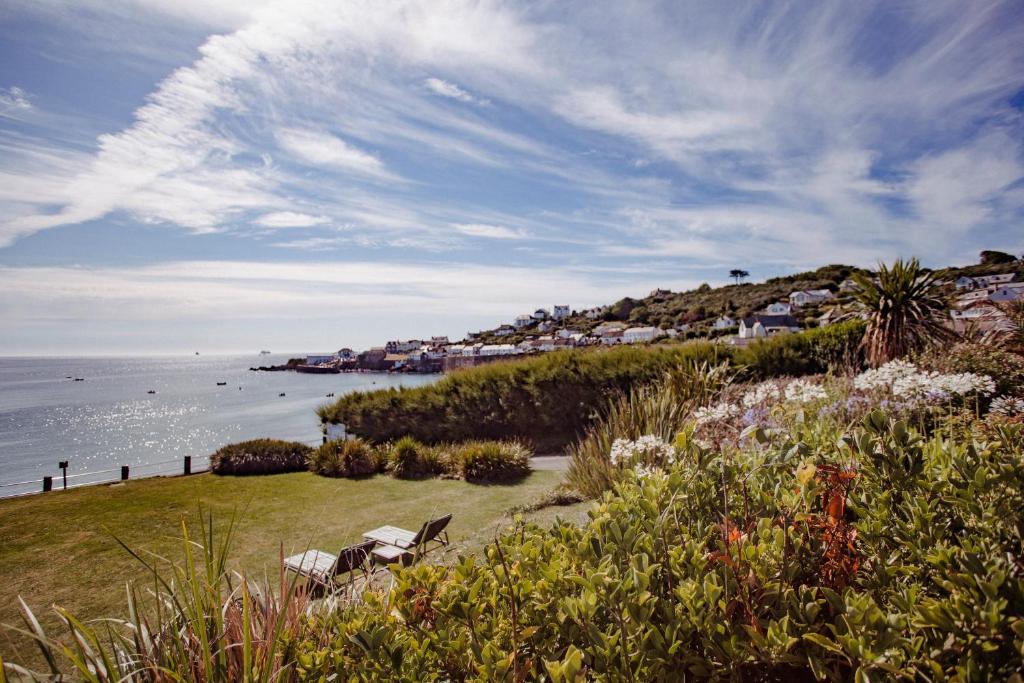 a beach with two chairs and the ocean with houses at The Bay Hotel in Coverack