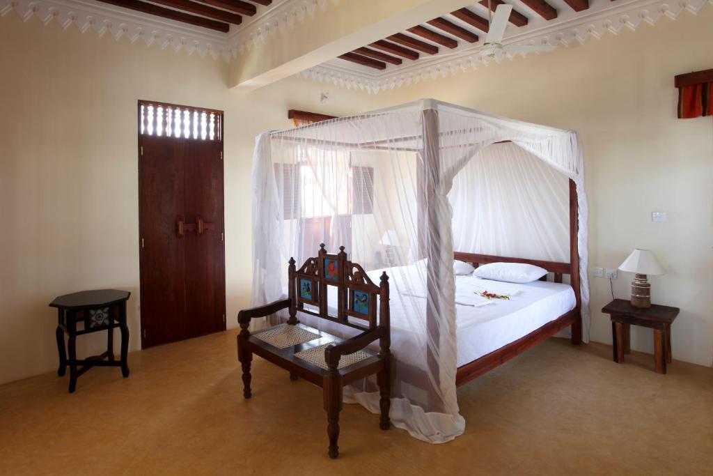 1 dormitorio con cama con dosel y silla en Msafini Hotel, en Lamu
