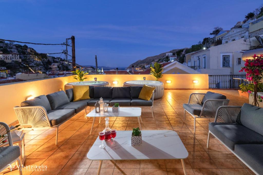 een patio met banken en tafels op een dak bij Maravelia's Rooms in Symi