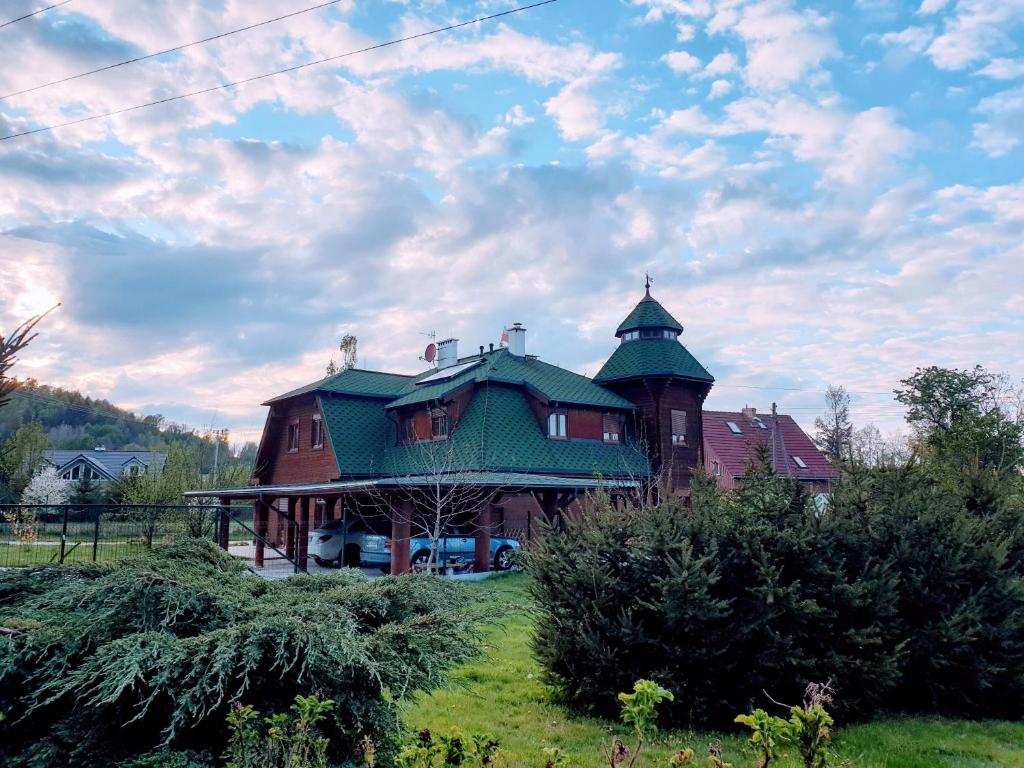 une grande maison avec un toit vert sur un champ dans l'établissement Sobieszów APARTAMENT KRZYSIO Zielone Wzgórze -Willa Tosia, à Jelenia Góra