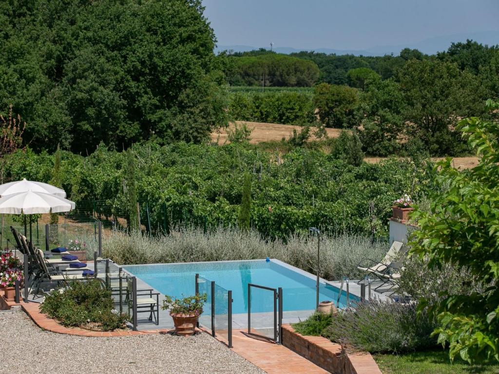 a swimming pool in a garden with chairs and an umbrella at Belvilla by OYO Villa Severina in Cortona