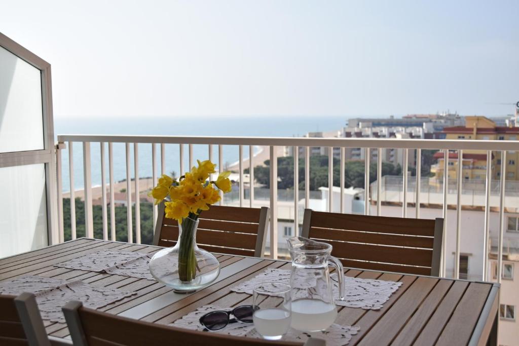 una mesa de madera con un jarrón de flores en el balcón en Apartamento Terraza Mar, en Malgrat de Mar
