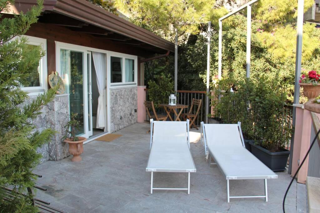 un patio con 2 bancos blancos y una mesa en Chalet vista mare a Taormina con parcheggio Paolone House, en Taormina