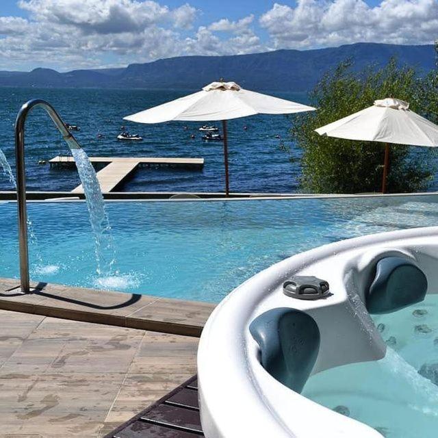 a swimming pool with a bath tub and an umbrella at Departamento Pucón - Salida directa al Lago Villarrica in Pucón