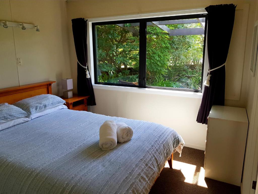 a room with a bed with a white towel on it at Estuary Retreat Whangamata in Whangamata