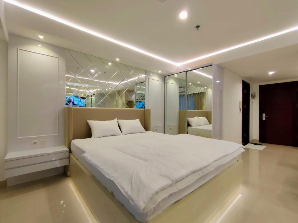 ein Schlafzimmer mit einem großen weißen Bett und einem Spiegel in der Unterkunft Platinum 1010 Studio Tera Apartemen Bandung City View in Bandung