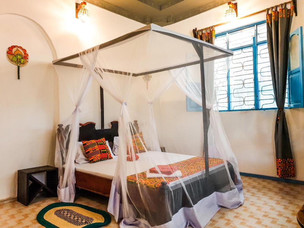 a bedroom with a canopy bed in a room at Déjà Blue in Paje