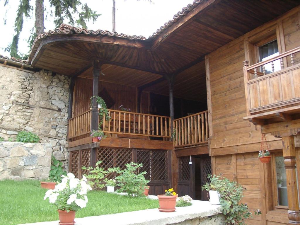 a wooden house with a balcony and potted plants at Sarafova Guest House in Koprivshtitsa