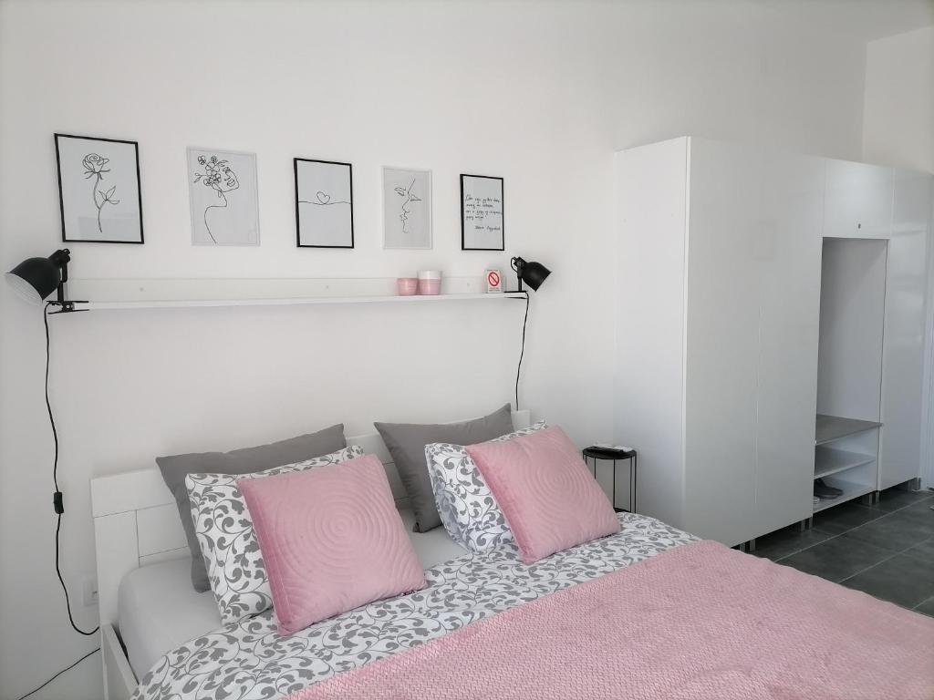 a bedroom with a bed with pink and grey pillows at SvjetlanAlex 2 in Banja Koviljača