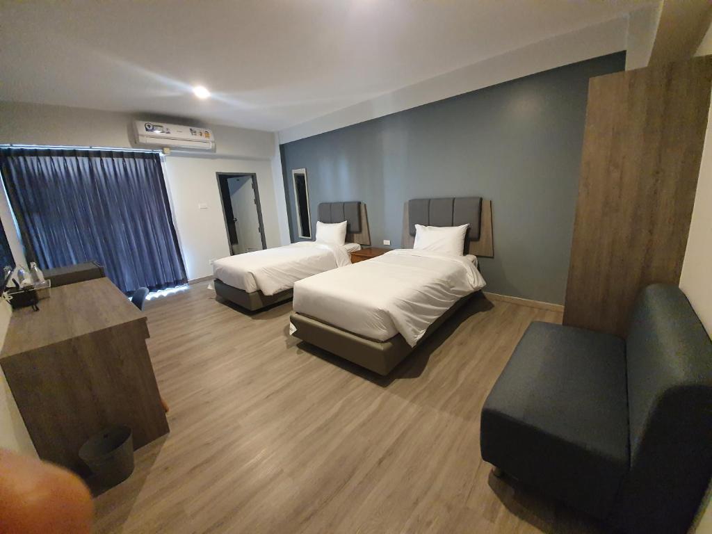 a hotel room with two beds and a couch at Neo Hotel in Khon Kaen