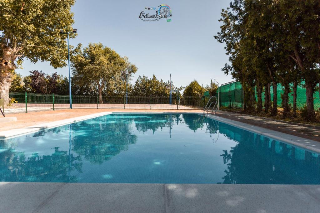 a swimming pool in a park with trees at Albergue Multiaventura Active Andalucia in Almodóvar del Río