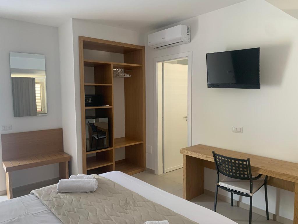 a bedroom with a bed and a desk and a television at Miriasol Bed and Breakfast in Capo Vaticano
