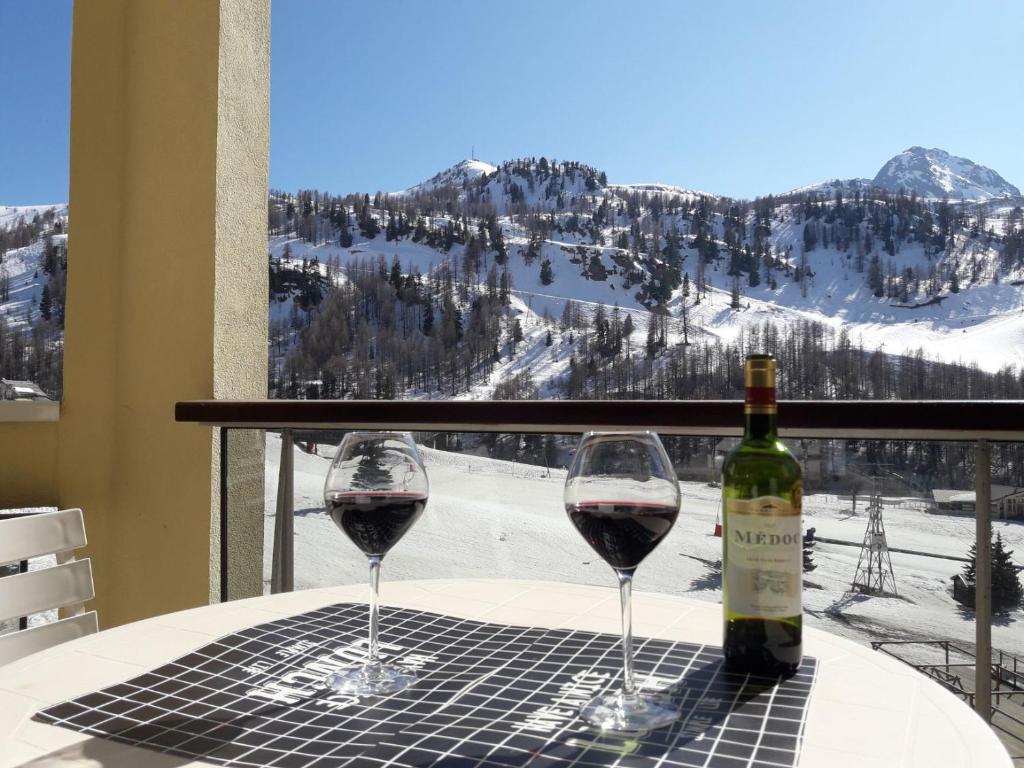 due bicchieri di vino rosso seduti su un tavolo con finestra di Appartement 4/6 pers plein sud. Front de neige a Isola 2000