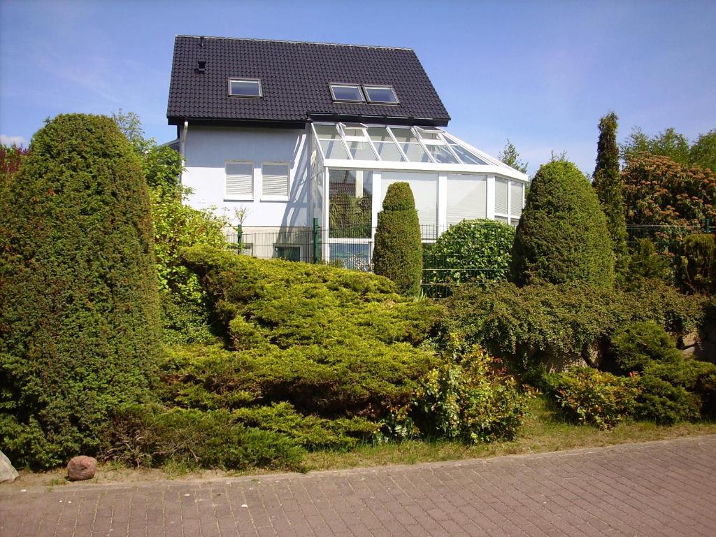 a white house with a black roof and some bushes at Ferienwohnung Liane in Sassnitz