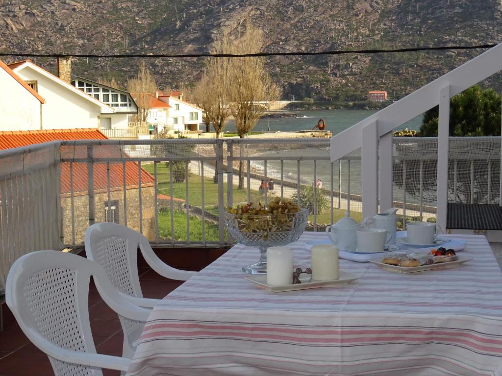 a table on a balcony with a view of the water at Apartamento Area Pequena Ézaro in Ézaro