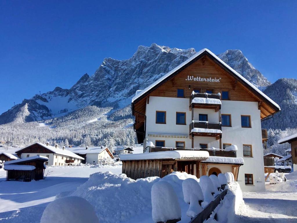 a snow covered building with mountains in the background at Das Wetterstein in Ehrwald