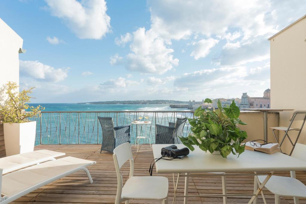 a balcony with a table and chairs and a view of the ocean at La Baia di Ortigia in Syracuse