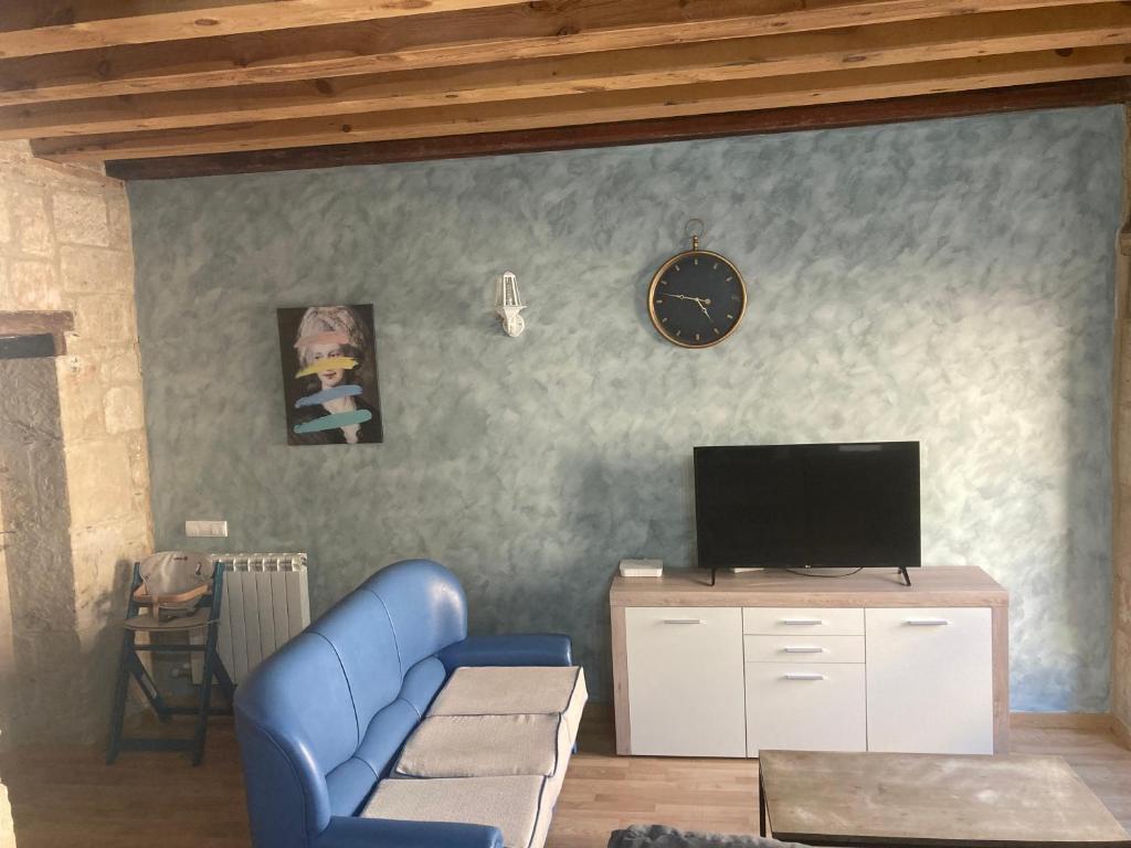 a living room with a blue couch and a clock at Apartamento S-XVIII la RANITA SALMANTINA in Salamanca