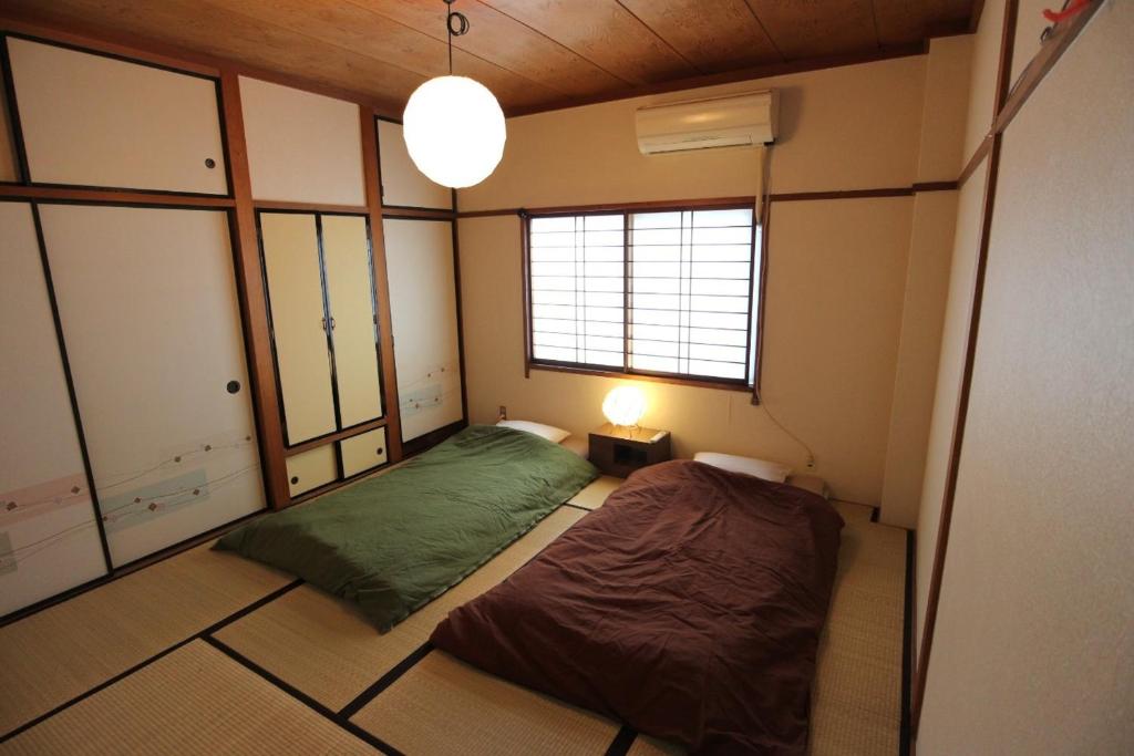 金沢市にあるリバーサイド ステイ 金沢のベッドと窓が備わる小さな客室です。