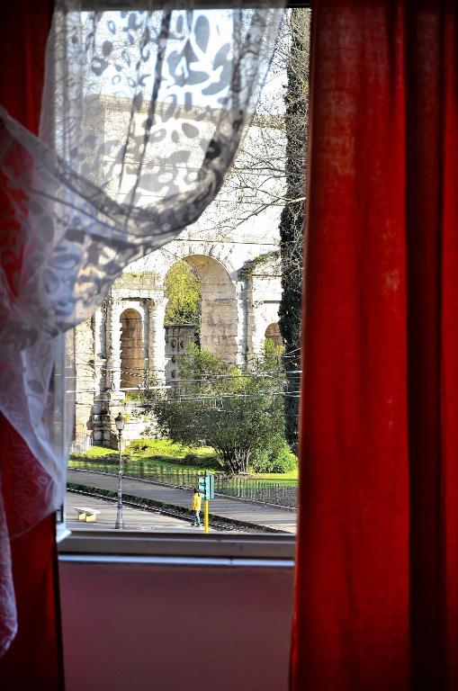 a window with a red curtain and a view of a building at Hostel Castello Maggiore in Rome