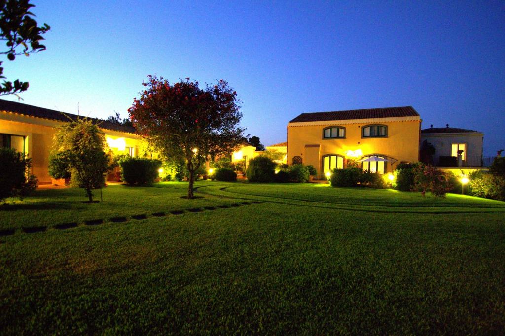 ein großes Haus mit Garten in der Nacht in der Unterkunft Torre Archirafi Resort in Riposto