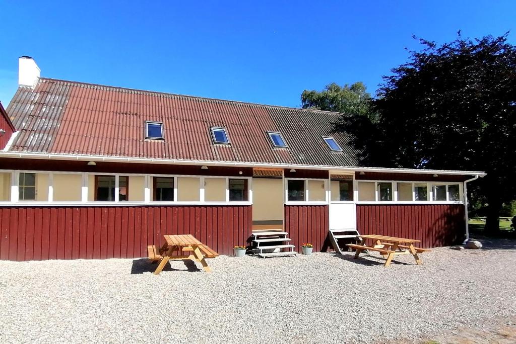 un edificio con dos mesas de picnic delante de él en Skovly FerieCenter, en Humble