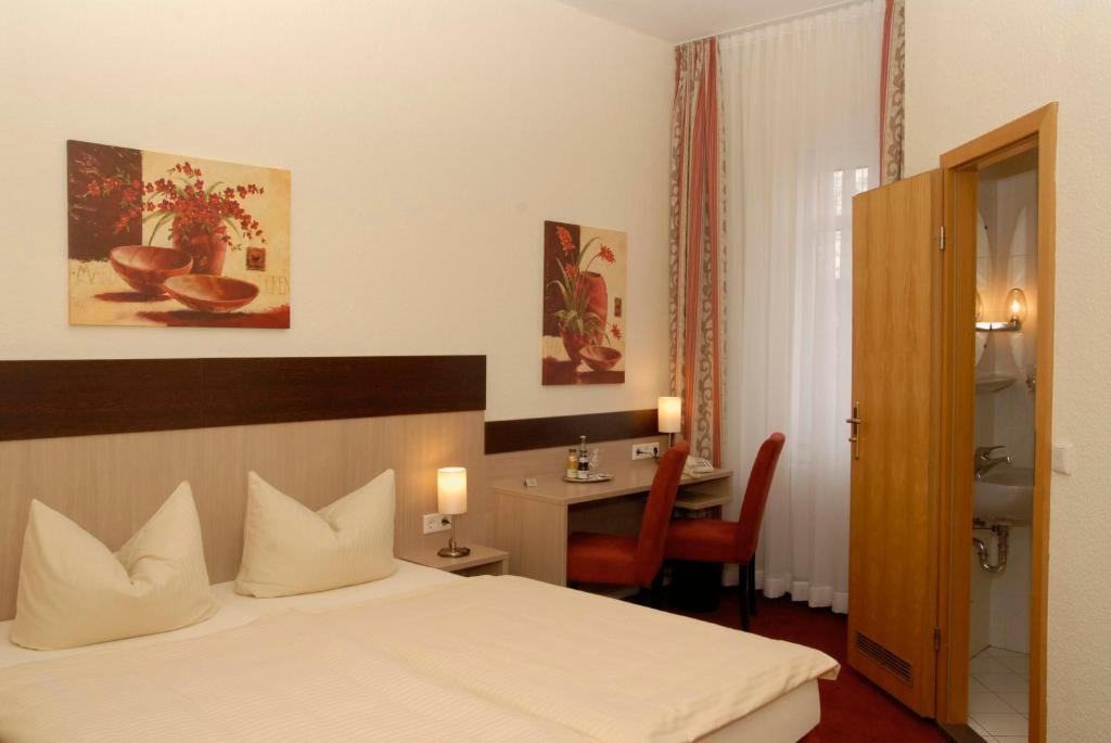 a bedroom with a bed and a desk with a chair at Hotel Wuppertaler Hof in Remscheid