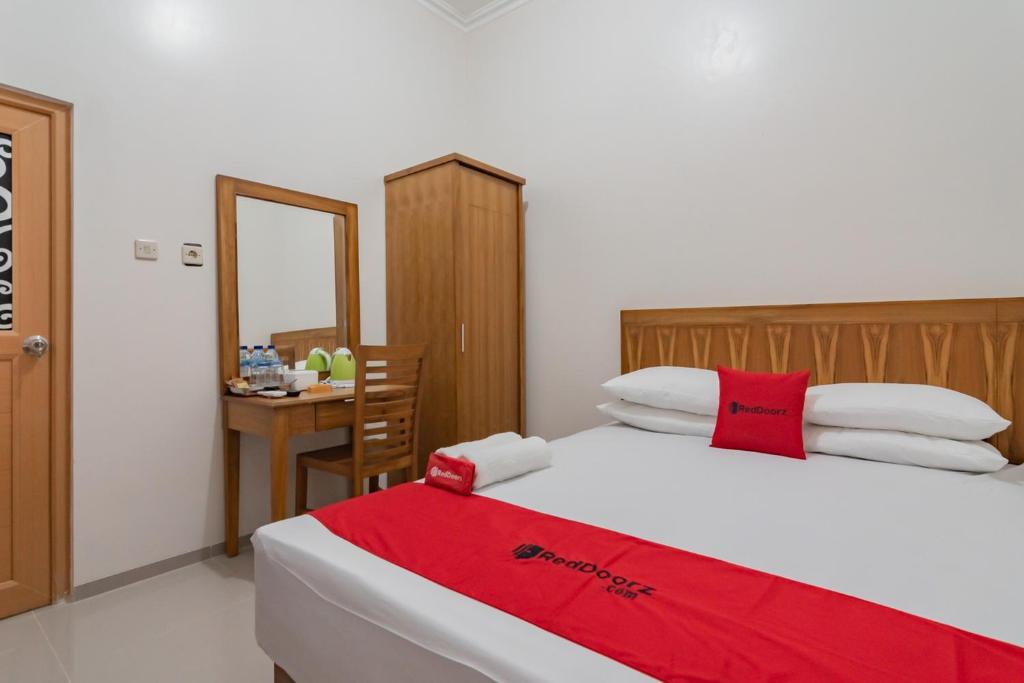 ein Schlafzimmer mit einem Bett mit einer roten Decke darauf in der Unterkunft RedDoorz Syariah Plus @ Perintis Guesthouse Tasikmalaya in Tasikmalaya